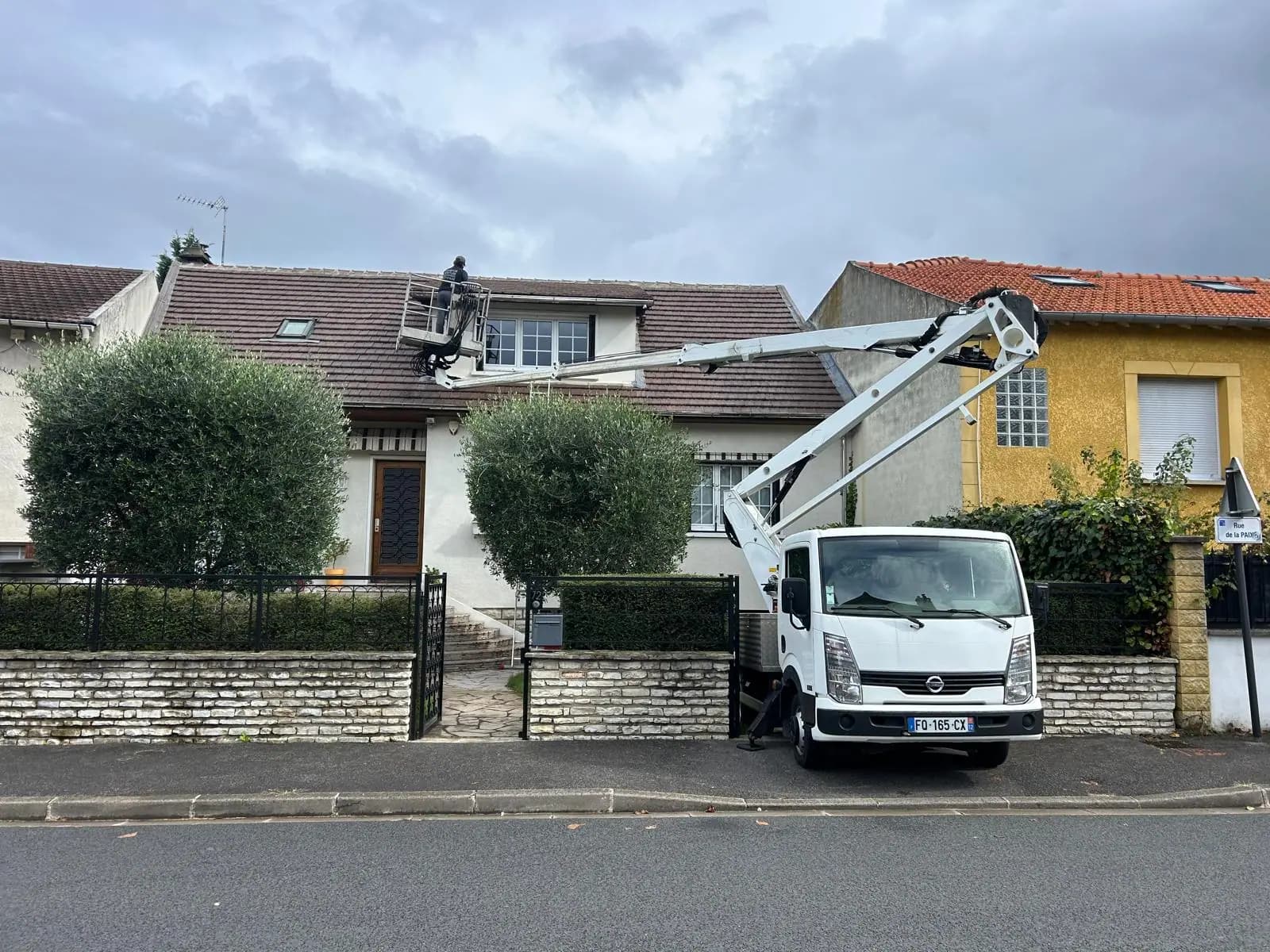 Camion-nacelle déployé devant un pavillon, opérateur en panier au niveau de la rive et de la gouttière — RW Couvreur
