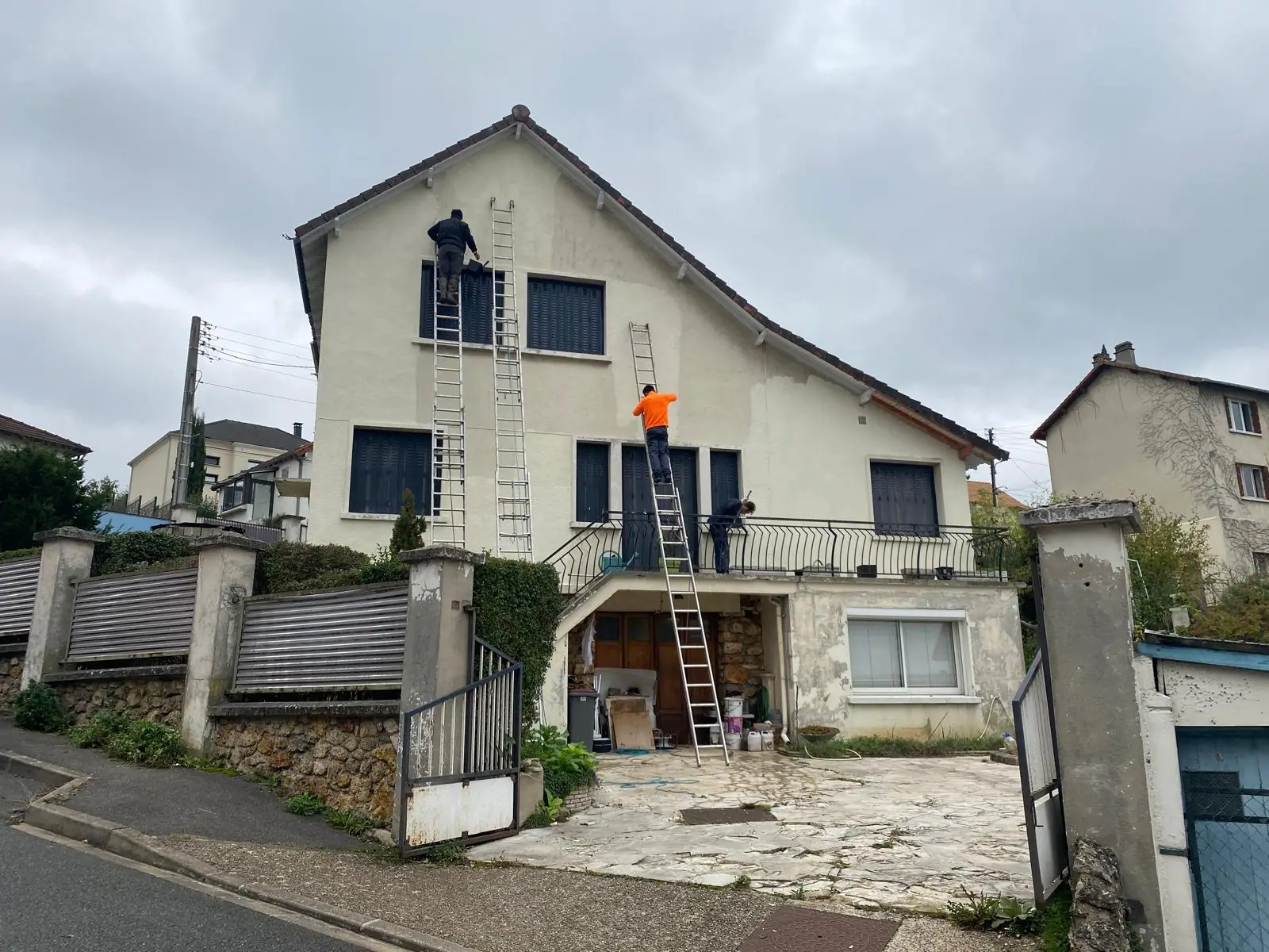 Trois ouvriers sur échelles en train de traiter la façade d'une maison — RW Couvreur