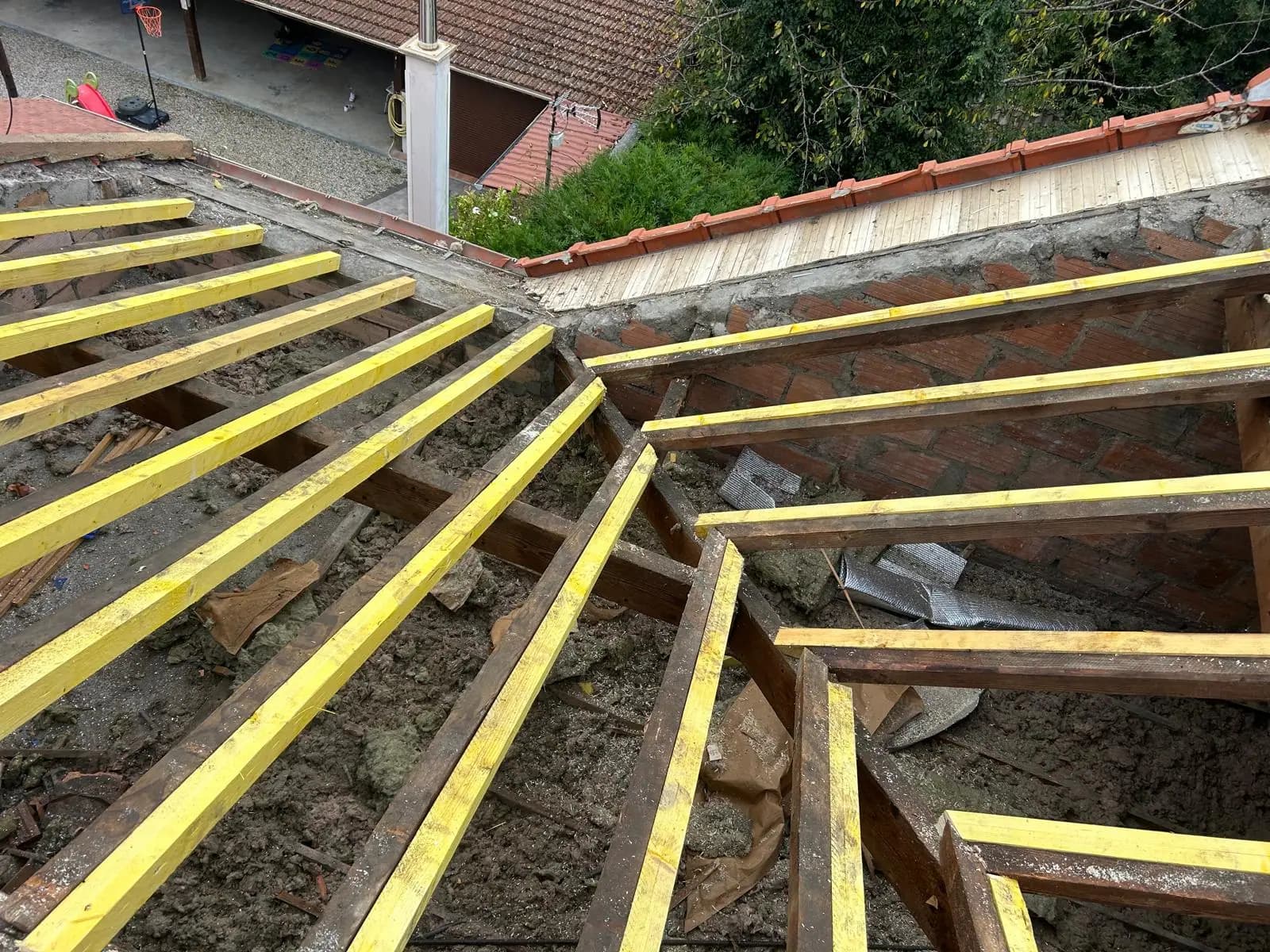 Chevrons neufs traités posés sur la maçonnerie à côté de l'ancienne charpente déposée — RW Couvreur
